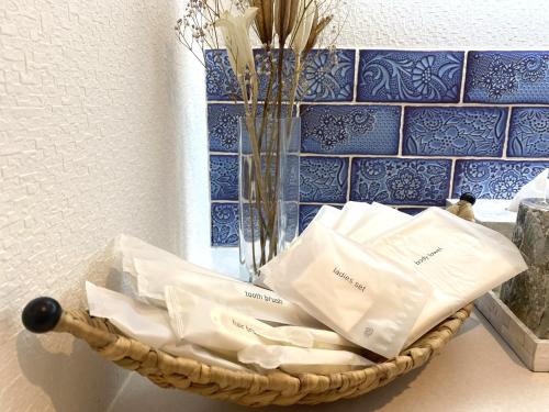 a basket filled with white towels next to a vase at H&H Calme in Minamiboso