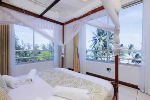 1 dormitorio con 2 camas y ventana grande en Beachfront Bliss Apartment, en Mombasa