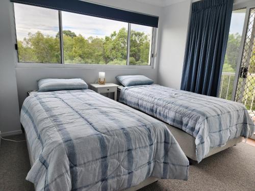 two beds in a room with a window at Fairways Golf & Beach Retreat Bribie Island in Woorim