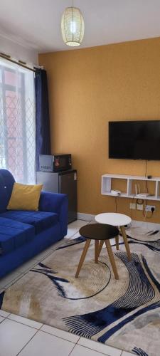 uma sala de estar com um sofá azul e uma mesa em Elfiehomes em Nairobi