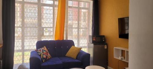 a living room with a blue chair in front of a window at Elfiehomes in Nairobi