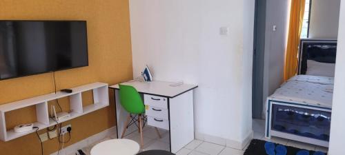 um pequeno quarto com uma secretária e uma cadeira verde em Elfiehomes em Nairobi