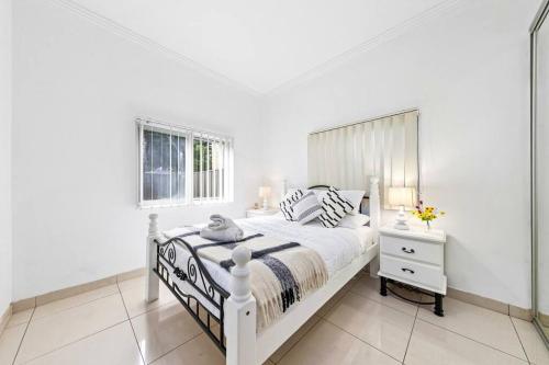 een witte slaapkamer met een wit bed en een raam bij Cozy 4 Bedroom House at Prime Location in Sydney