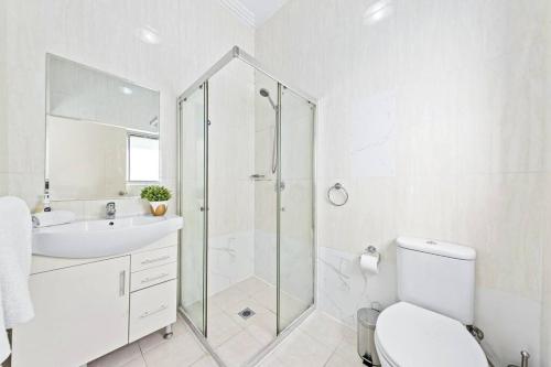 een badkamer met een douche, een toilet en een wastafel bij Cozy 4 Bedroom House at Prime Location in Sydney