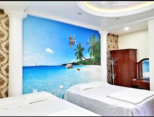 HAPPY GUEST HOUSE في هاي فونج: غرفة نوم بسريرين و لوحة جدارية لشاطئ