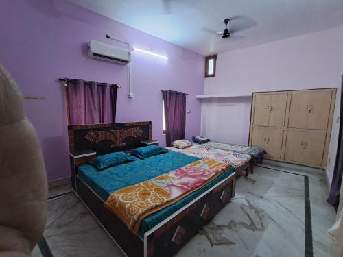 1 dormitorio con 2 camas y paredes moradas en Satwik Homestay, en Ayodhya