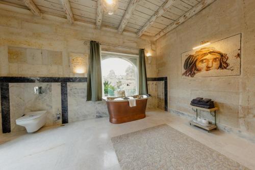 ギョレメにあるAza Cave Cappadocia Adult Hotelのバスルーム(バスタブ、トイレ付)、窓が備わります。