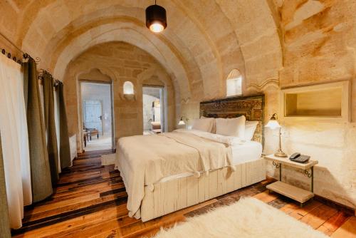 Aza Cave Cappadocia Adult Hotel في غوريمِ: غرفة نوم بسرير كبير في جدار حجري