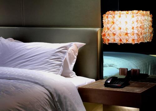 a bedroom with a bed and a nightstand with a mirror at Sheraton Hsinchu Hotel in Zhubei