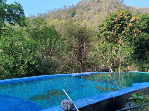 una piscina con una montaña en el fondo en Marine Drive Retreat, en Rishīkesh