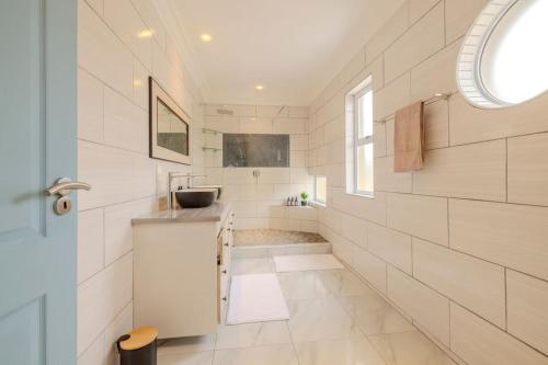 Baño blanco con lavabo y bañera en The Waterfront Cottage F3, en Swakopmund