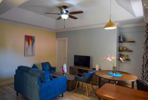 a living room with blue chairs and a table at Sea Piton View Apartment- Location, Convenience, Modern Living in Soufrière