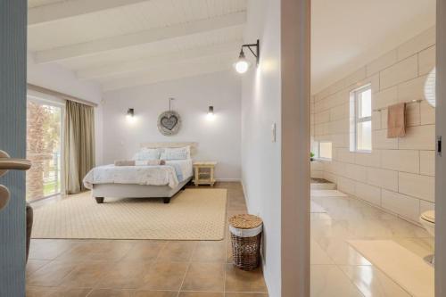 a white bedroom with a bed and a bathroom at The Waterfront Cottage F3 in Swakopmund