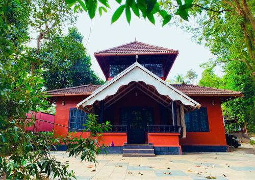 un edificio rojo con una puerta delante de él en The Stream View Villas Wayanad en Vythiri