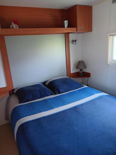 Lombez的住宿－Mobilhome cosy au calme de la campagne，一间卧室配有一张带蓝色棉被的床