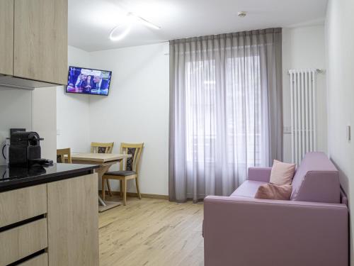 a living room with a purple couch and a kitchen at Liz Hotel & Apartments in Predazzo