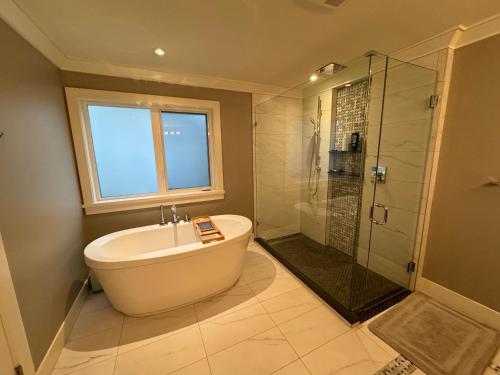 La salle de bains est pourvue d'une baignoire et d'une douche en verre. dans l'établissement Charming Modern Home Near Downtown and UBC, à Vancouver