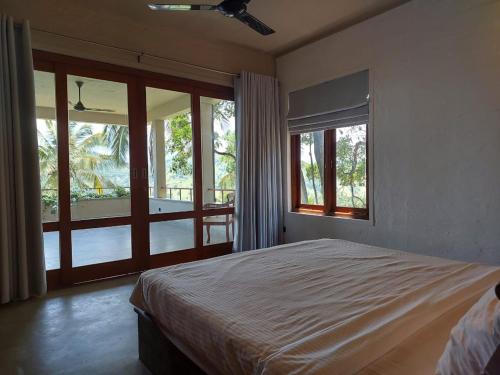 Par 5 Golf Villa في ديغانا: غرفة نوم بها سرير وبلكونة بها نوافذ
