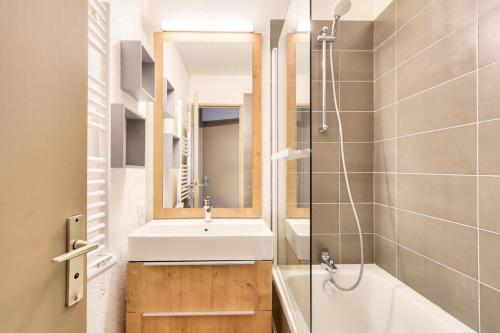 une salle de bain avec un lavabo, une baignoire et un miroir dans l'établissement Résidence Les Fontaines Blanches - maeva Home - Appartement 2 pièces 5 personnes - Sélection MAE-5721, à Morzine