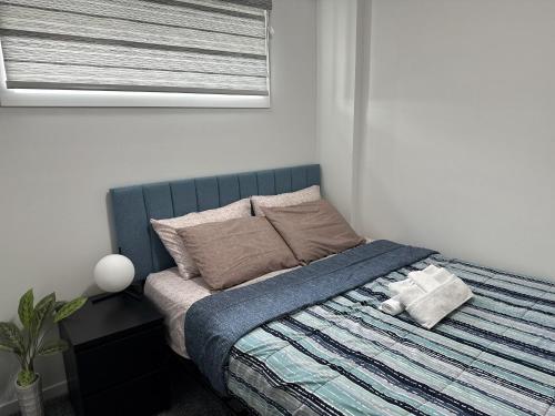 een slaapkamer met een bed met een blauwe deken en een raam bij Tee's Haven in Calgary