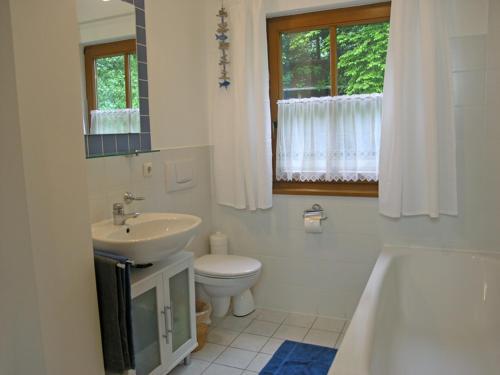 a bathroom with a sink and a toilet and a tub at Ferienwohnung Anderl in Gstadt am Chiemsee