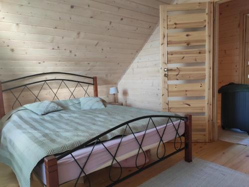 a bed in a room with a wooden wall at Kwietna łąka na szlaku in Jarnołtówek