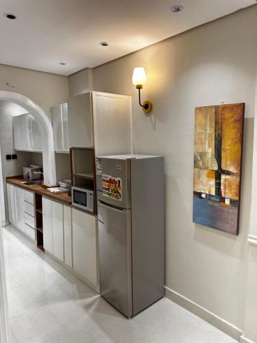a kitchen with a stainless steel refrigerator and a painting at Mangroves luxury suites in Al Madinah
