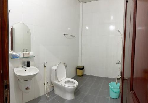 a white bathroom with a toilet and a sink at ROSE MOTEL in Phum Lovéa