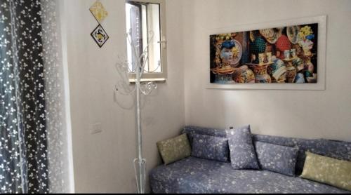 ein Wohnzimmer mit einem blauen Sofa und einem Gemälde in der Unterkunft Casetta Blu Mondello zona Partanna in Palermo