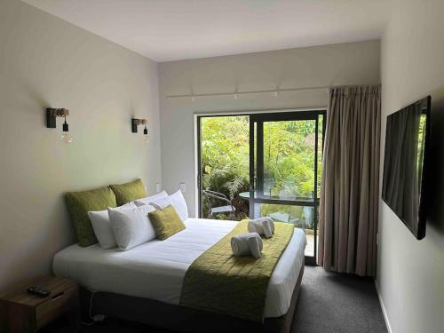 a bedroom with a large bed and a large window at Forest View Franz Josef in Franz Josef