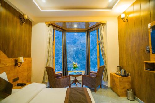 a bedroom with a bed and a table and a large window at Tapovan Inn Hotel And Resort in Joshīmath