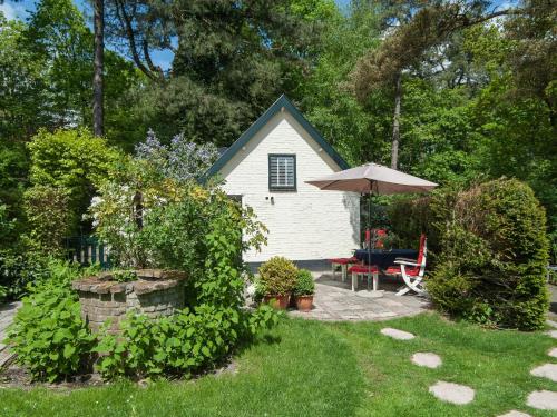 ein kleines weißes Haus mit einem Sonnenschirm und einer Terrasse in der Unterkunft Pleasing Holiday Home in Schoorl with Patio in Schoorl