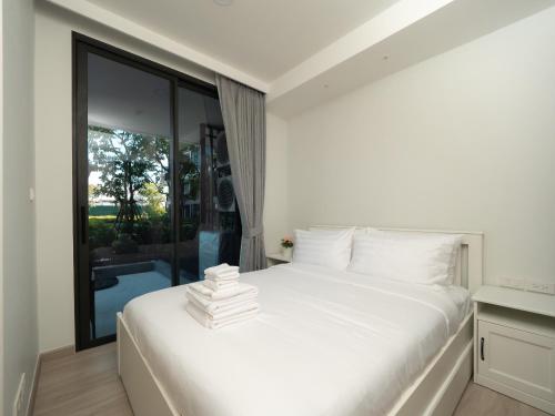 ein Schlafzimmer mit einem weißen Bett und einem großen Fenster in der Unterkunft Excellent 2bd apartment with a patio in Phuket