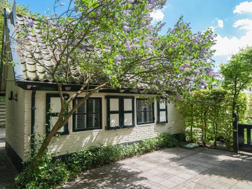 ein Haus mit einem blühenden Baum davor in der Unterkunft Pleasing Holiday Home in Schoorl with Patio in Schoorl