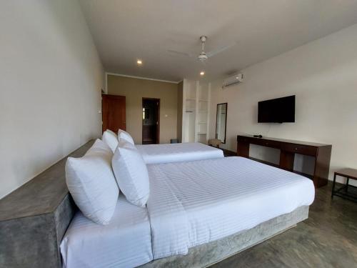 a large white bed with white pillows in a bedroom at Par 5 Golf Villa in Digana