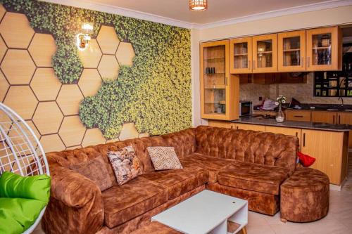 a living room with a brown couch and a kitchen at Dandy Home, 2 BdRm, Estn Bypass Kamakis Greenspot in Ruiru