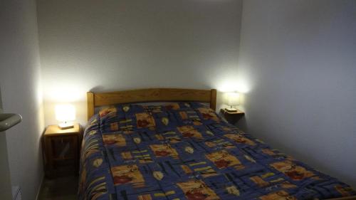 Ce lit se trouve dans une chambre avec 2 lumières sur 2 tables. dans l'établissement Résidence Arches - RESIDENCE LES ARCHES 4-6 PERSONNES MAE-1271, à Saint-Lary-Soulan