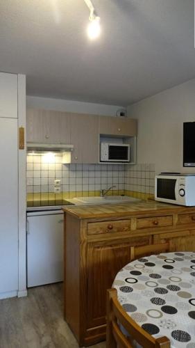 - une cuisine avec des placards en bois, une table et un four micro-ondes dans l'établissement Résidence Arches - RESIDENCE LES ARCHES 4-6 PERSONNES MAE-1271, à Saint-Lary-Soulan
