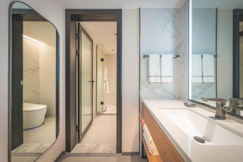 a bathroom with a sink and a mirror at UrCove by HYATT Nanjing Downtown in Nanjing