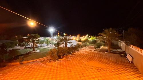 a night view of a park with palm trees and lights at Thenoblejewel in Al Laqīţah