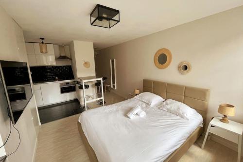 a bedroom with a white bed and a kitchen at Le Studio Saint Georges in Nancy