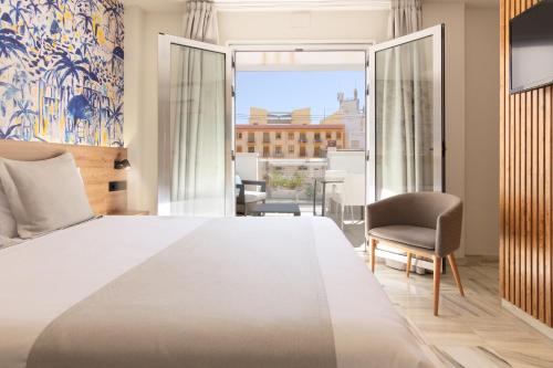 a bedroom with a large white bed and a chair at Hotel La Milagrosa in Alicante