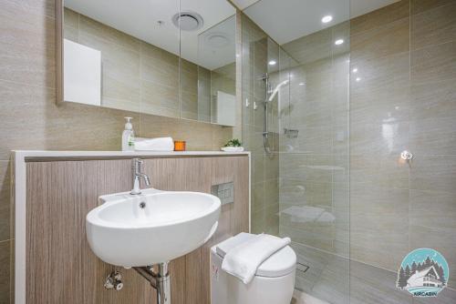 ein Bad mit einem Waschbecken und einer Glasdusche in der Unterkunft Aircabin - Zetland - Lovely - 2 Beds Apt Free Park in Sydney
