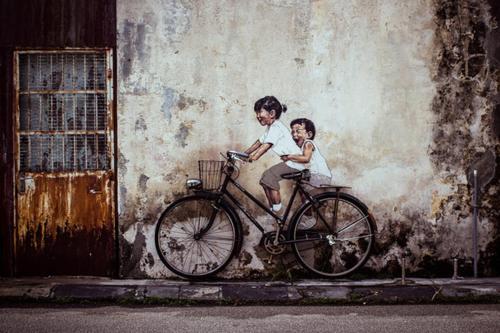 a painting of a woman and a child on a bike at Little India Heritage Villa in George Town