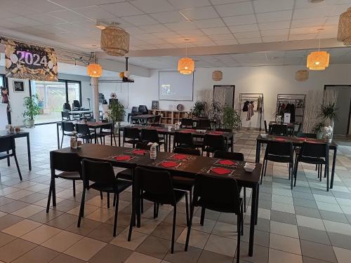 a restaurant with tables and chairs in a room at LOVE SPA in Oye-Plage