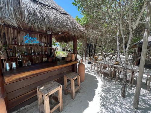 un bar con bancos y una cabaña de paja en Hotel Casa Punta Coco & Beach Club - Adults Only, en Isla Holbox