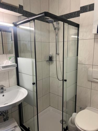 a bathroom with a shower and a toilet and a sink at Hotel Aggertal in Gummersbach