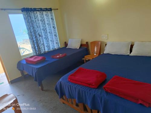 a room with two beds with red pillows on them at Gokarna Govekar Sea Facing Rooms in Gokarn