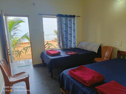 a room with two beds and a window with a view at Gokarna Govekar Sea Facing Rooms in Gokarn