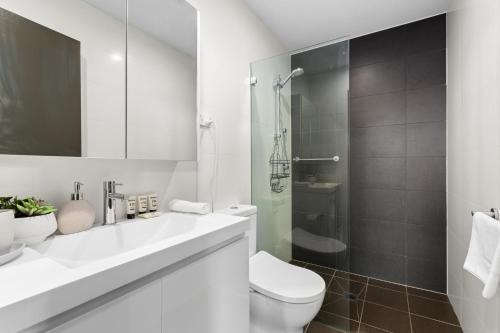 a white bathroom with a toilet and a shower at Elegant 1-Bed by Riverside Park & Amenities in Sydney